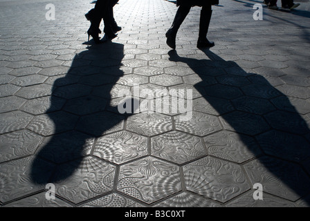 Shadows of two people walking on tiled streets