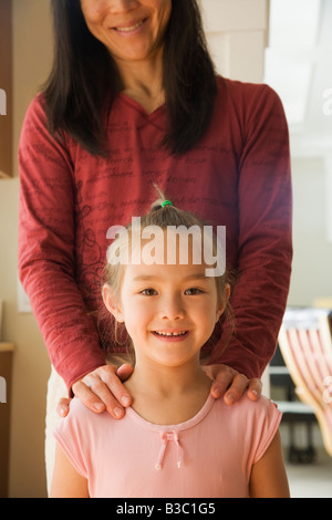 Asian mother with hands on daughter’s shoulders Stock Photo