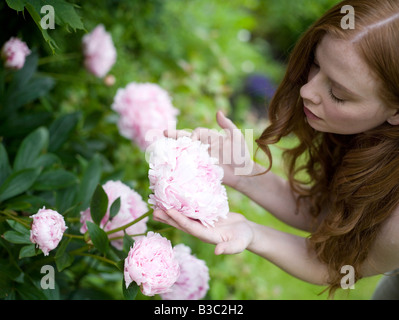 A woman admiring her flowers in a garden Stock Photo