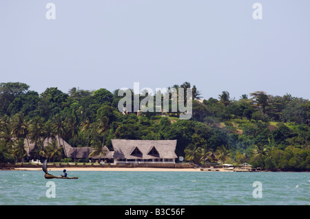 Kenya, Kilifi. A local fisherman sails his dugout canoe in front of a lodge on the shores of Kilifi Creek. Stock Photo
