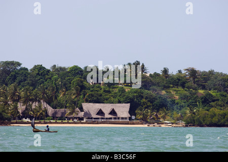 Kenya, Kilifi. A local fisherman sails his dugout canoe in front of a lodge on the shores of Kilifi Creek. Stock Photo