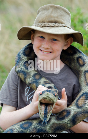 Kenya, Masai Mara National Reserve. Young boy on safari in the Masai Mara playing with a toy snake (MR). Stock Photo