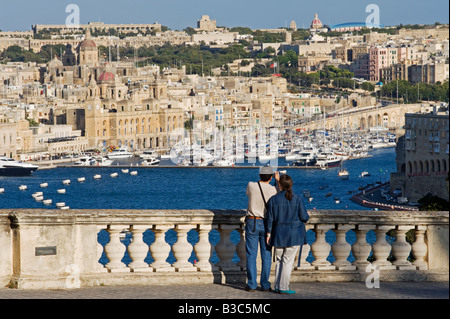 Malta, Valletta. Tourists look out from an elegant ballustrade on the old walls of Valletta over the Grand Harbour towards Vittoriosa. Stock Photo