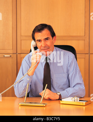 Businessman talking over phone while sitting in office Stock Photo
