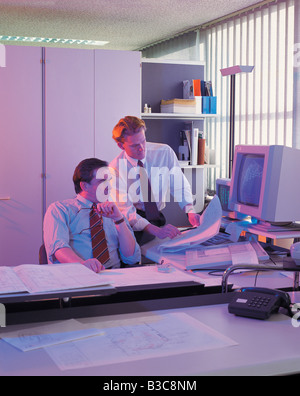 Businesspeople watching blueprints in office Stock Photo