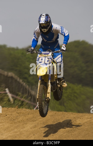 Solo motocross rider jumps mound with sandy track and shadow below Stock Photo