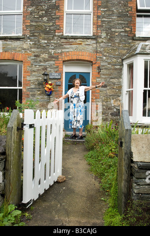 Happy lady pensioner in front of her cottage home. Stock Photo