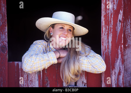 Cowgirl looking through barn window barn Stock Photo
