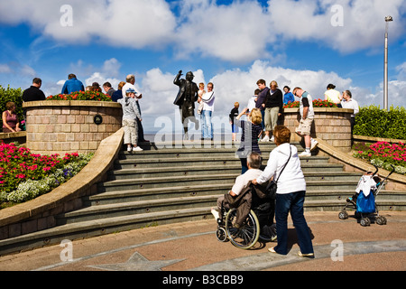 Tourists having their picture taken with the Eric Morecambe bronze statue at Morecambe, Lancashire, North of England, UK Stock Photo
