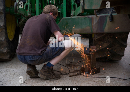 Making a repair using an angle grinder at the back of a Tractor Stock Photo