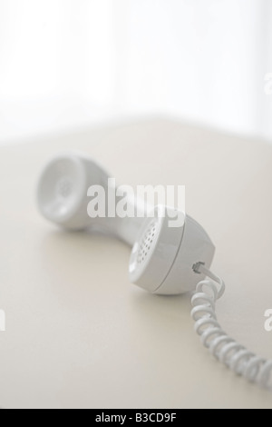 telephone receiver off the hook on table Stock Photo