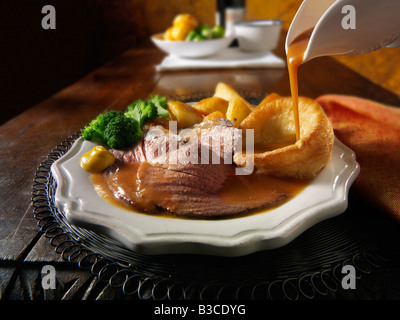 Traditional British roast dinner with roast beef, roast potatoes, yorkshire puddings and onion gravy. 21 days hung Stock Photo