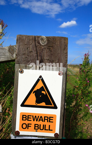 A warning sign stating 'BEWARE OF BULL' on a gatepost. Stock Photo