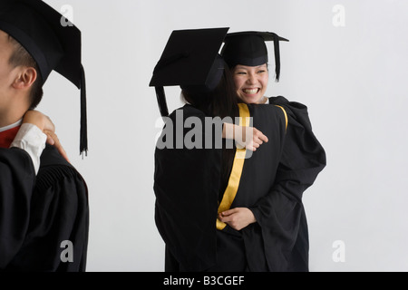 Two young female graduates hugging each other and smiling Stock Photo