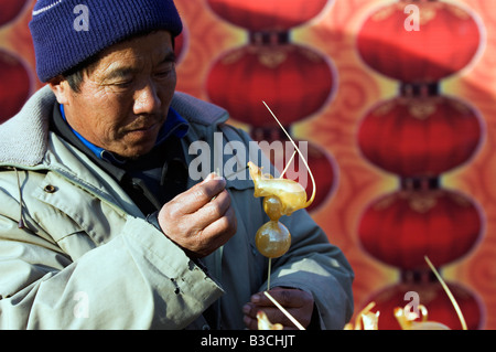 China, Beijing. Chinese New Year Spring Festival - a man making mouse shaped sugar candy in the year of the rat at Longtanhu Stock Photo
