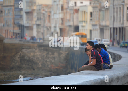 Young people sitting on a wall Malecón Havana Habana Cuba Caribbean Stock Photo