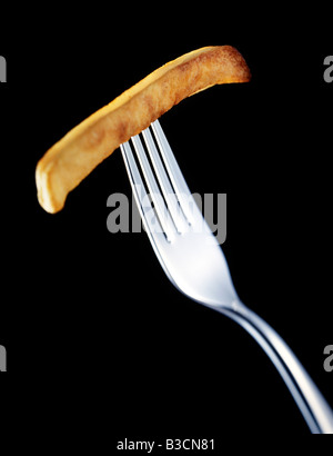 A cooked chip on the end of a dinner fork Stock Photo