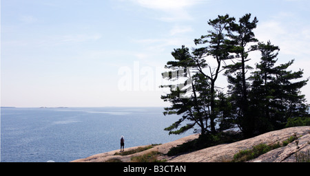 Lone man on rocky island in front of vast water of Georgian Bay Stock Photo