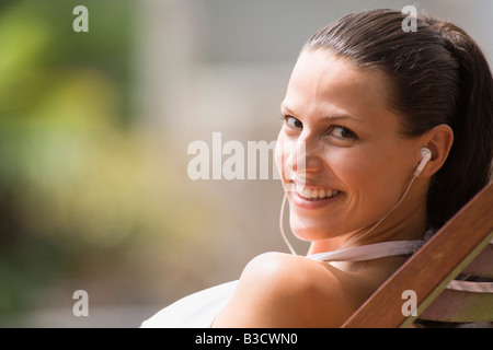 Young woman in deck chair listening to MP3-Player, portrait Stock Photo