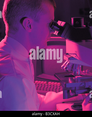 Technician looking through microscope in hospital laboratory. Stock Photo