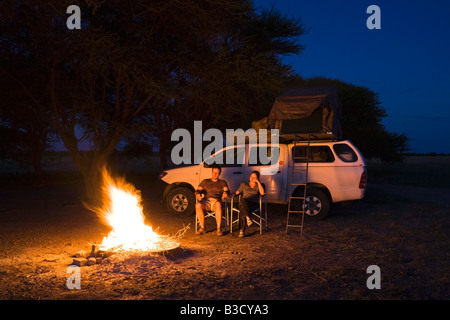 Africa, Botswana, Two persons by camp fire Stock Photo