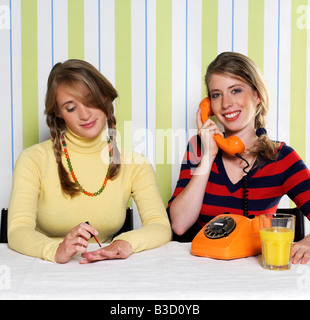 Two teenage girls (16-17), one using phone, the other painting nails, portrait Stock Photo
