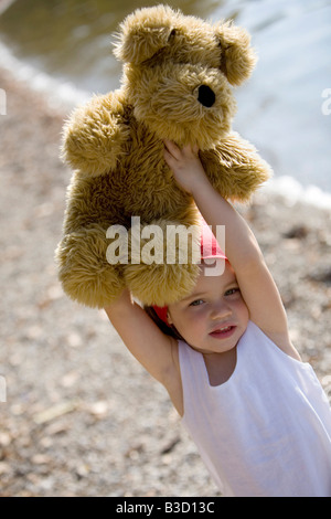 Germany, Bavaria, Ammersee, little girl (3-4) lifting teddy bear Stock Photo