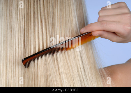 Young woman combing her hair, rear view Stock Photo