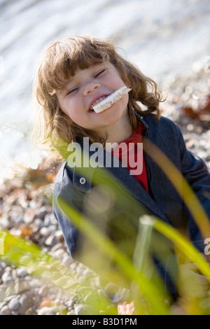 Germany, Bavaria, Ammersee, little girl (3-4) bread in mouth Stock Photo