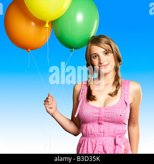 Teenage girl (16-17) holding bunch of balloons, smiling, portrait Stock Photo