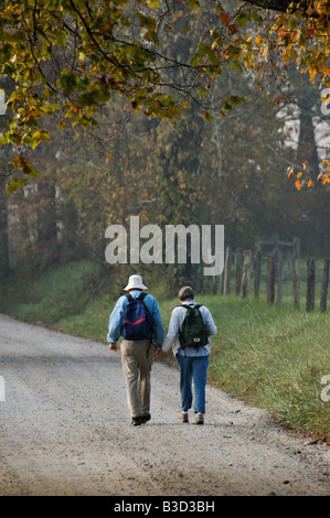Older Senior Couple Holding Hands while Walking Down Fence Lined Country Lane in Cades Cove Great Smoky Mountains National Park Stock Photo