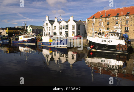 The picturesque scenic fishing port of Eyemouth in the Scottish Borders fishing boats and harbour side houses reflected in sea Stock Photo