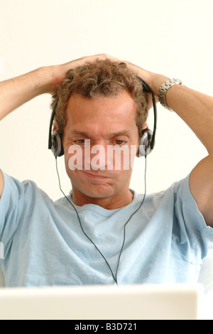 man looking at laptop computer screen with a confused expression on his face Stock Photo