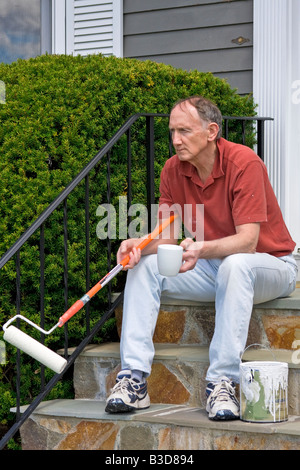 Senior man having a coffee break from painting Stock Photo