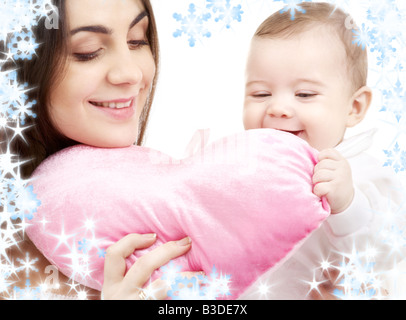 happy baby and mama with heart shaped pillow and snowflakes Stock Photo