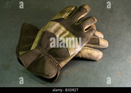 A pair of heavy-duty work gloves on a metal workbench Stock Photo