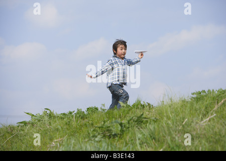 Boy running with paper airplane in park Stock Photo
