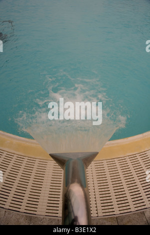 Fountain tap gushing water into a swimming pool. Stock Photo