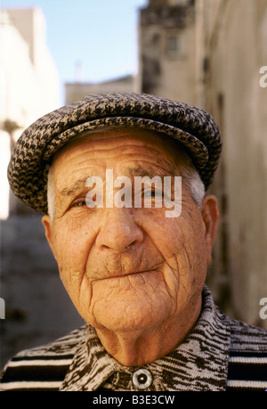 AN ELDERLY SICILIAN MAN WEARS A TWEED CAP AND SMILES WITH HIS LIPS SHUT Stock Photo