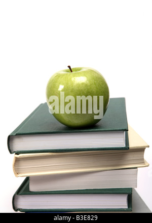 A shiny green apple on a pile of text books Stock Photo