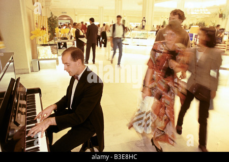 man playing the piano inside Harrods department store, London Stock Photo