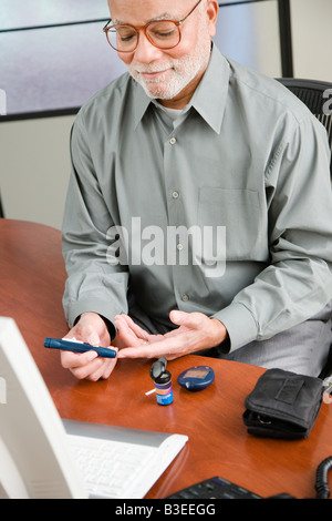 A man doing a home blood glucose testing Stock Photo