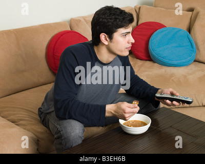 Man with food watching television Stock Photo