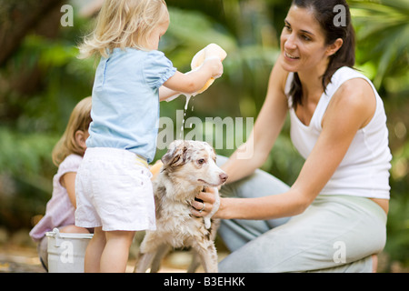 Mother and daughters washing dog Stock Photo