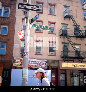 A young woman waiting on Leroy and Bleecker Street under a street sign and a signpost in Greenwich Village, NYC June 2008 Stock Photo