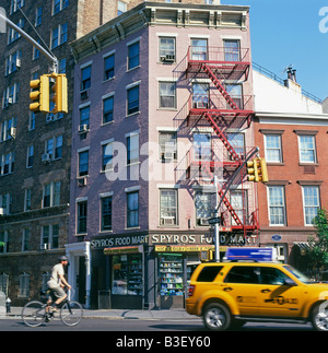 Man cycling across a road junction near Spyros Street Market and street scene on 8th Avenue near Bleecker Street NY KATHY DEWITT Stock Photo