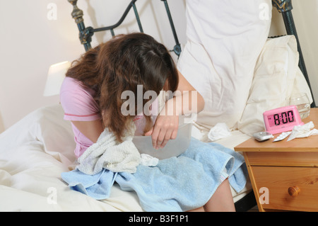 a girl in bed feeling sick with a sick bowl Stock Photo
