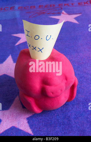 Upturned red piggy bank with I O U note on 500 Euro note towel background Stock Photo