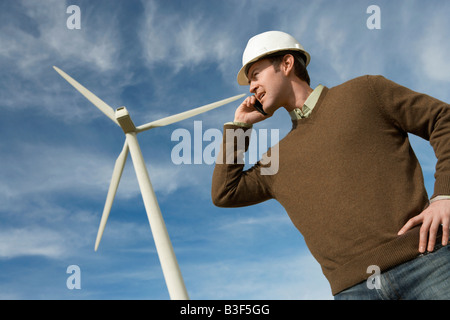 Engineer using mobile phone at wind farm Stock Photo