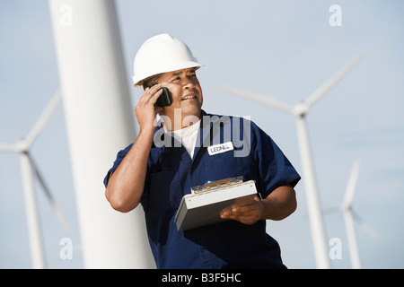 Engineer using mobile phone at wind farm Stock Photo
